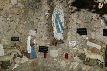 Grotte mit einer Statue der Muttergottes von Lourdes und zahlreichen Kerzen 